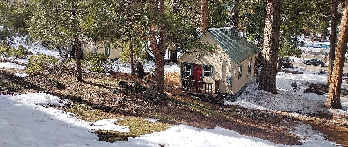 A sub-aerial view of the exterior of Shaver Lake Village Hotel surrounded by trees and fallen snow.