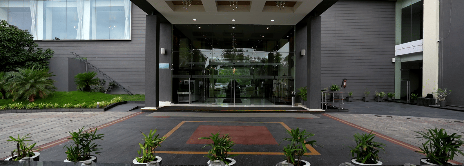 Entrance of the hotel with landscaped garden at Narayani Heights Hotel & Resorts, Ahmedabad.