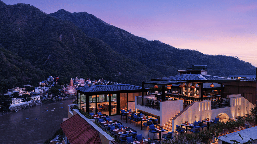 Aerial view of The Terrace at Aloha on the Ganges, Rishikesh, featuring rooftop dining, illuminated seating, and the surrounding Himalayan hills at dusk.