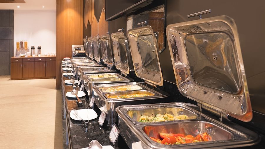 A buffet line at Lords Inn Udaipur displays various covered food warmers on a black countertop, ready for service.