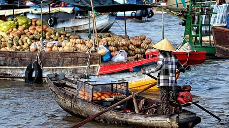 An overview of a floating market in the Mekong River with people on boats selling many items.