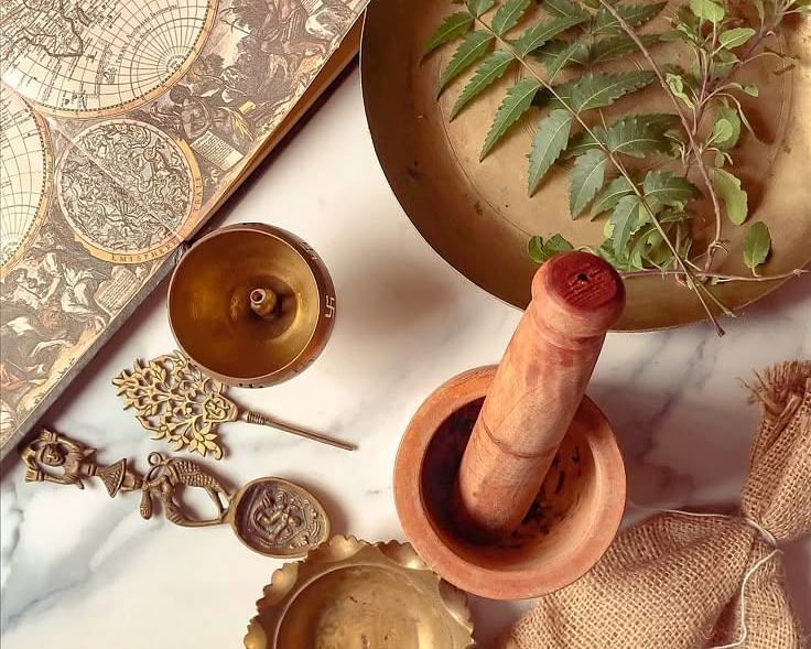 A collection of items on a surface, including bowls, a mortar and pestle, and what appear to be natural elements like leaves or herbs.