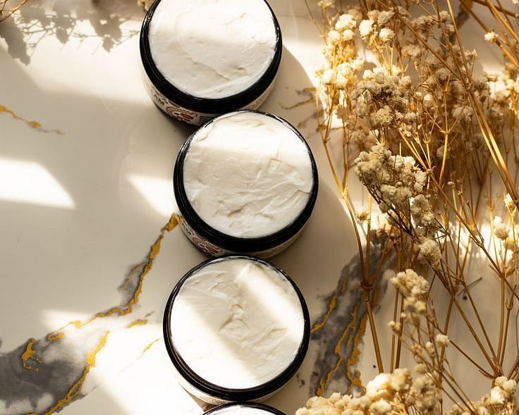 Stacked skincare jars placed on a gold-leaf background with warm lighting.