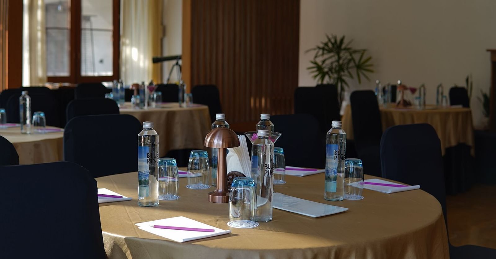 A conference room seating arrangement with a water bottles and notepads placed on the table at Saraca Resort & Spa Corbett