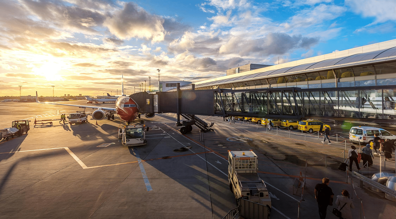 An airport terminal with airplanes visible through large windows and a bright, sunny sky outside.