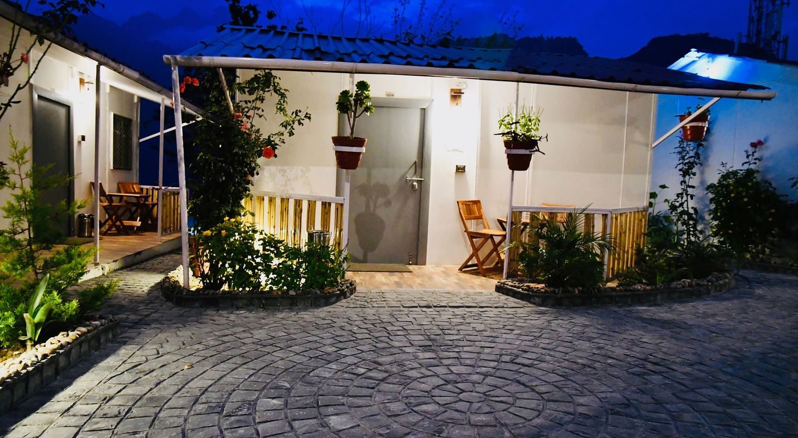 facade image of the deluxe room exterior during the night with stone pathway in front of it - The Tattva Boutique Resort