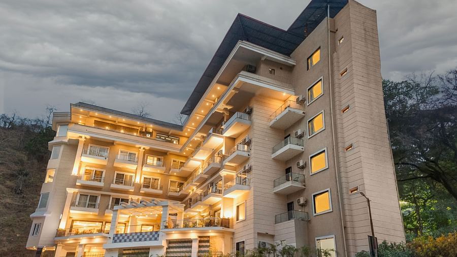 Facade of Stone Wood Hotel, Rishikesh with a cloudy sky in the background.