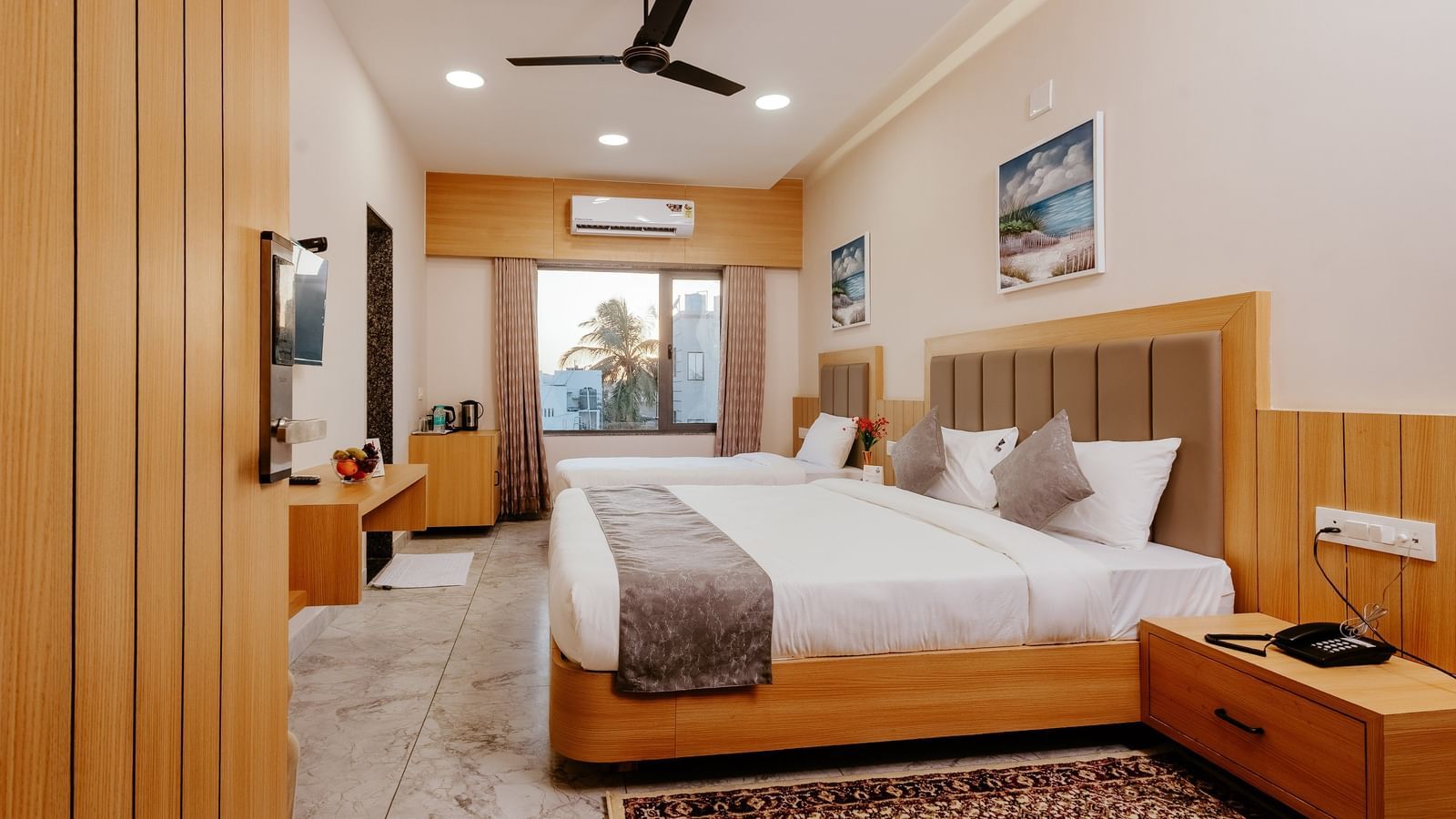 Spacious Pride Room at Daksh The Grand Gowardhan, Dwarka, with multiple beds, modern decor, and a view from the window at the far end.