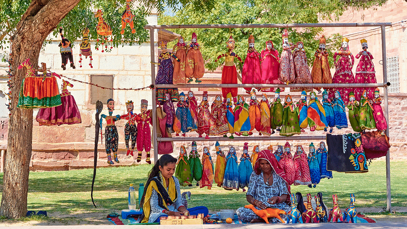 A roadside stall with two women selling traditional Indian puppets.