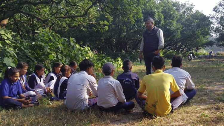 A person teaching the importance of recycling to a group of students at Golden Tusk