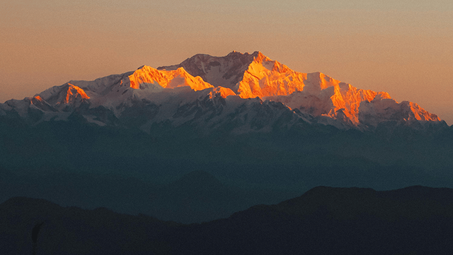 First light illuminating the Kanchenjunga mountain range as seen from Tiger Hill at sunrise.