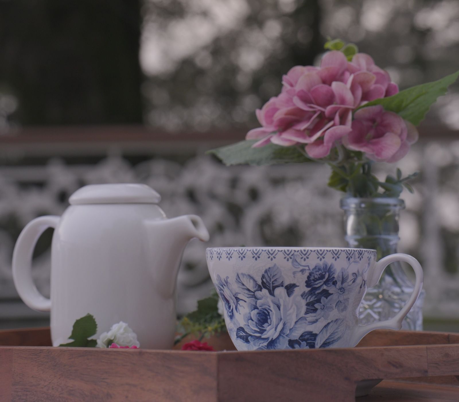 Outdoor tea setup with floral crockery and fresh pink flowers in soft focus - Mayfair Cafe & Suites, Dalhousie
