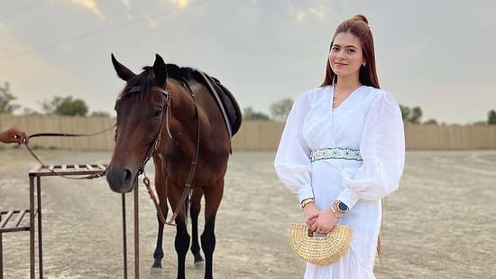 a woman standing by a Horse at inflated trampoline surrounded by trees at Themis Mudhouse - A Nature's Retreat Resort & Wellness