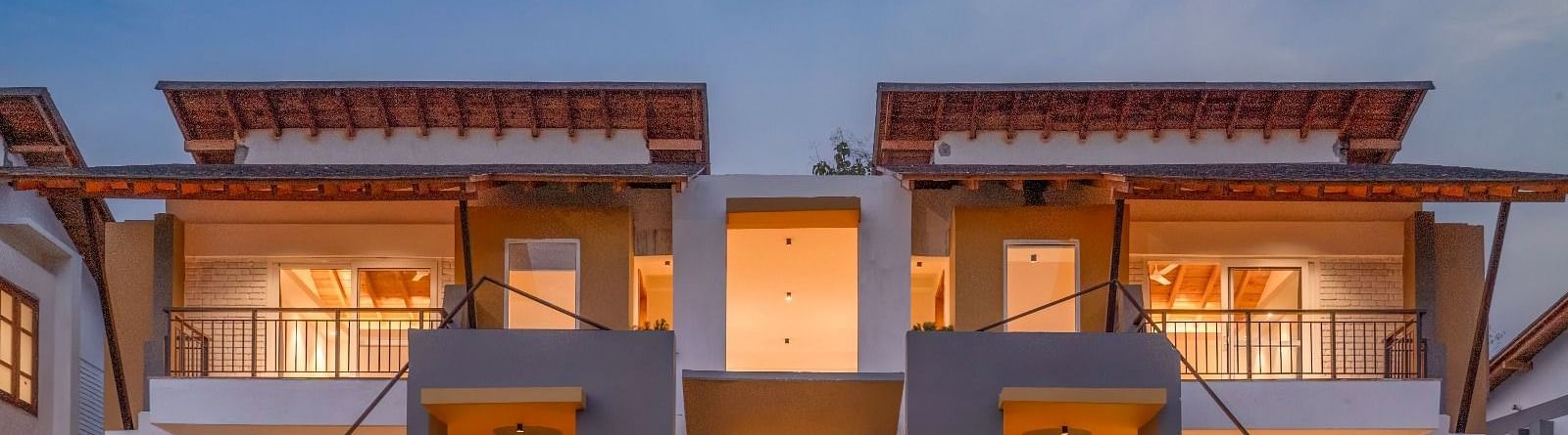 A row of modern houses with balconies, lit up at night.