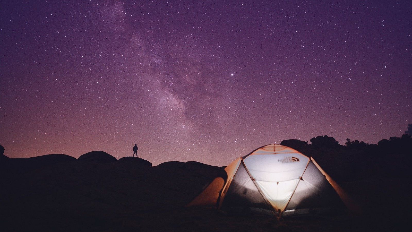 an image of a tent under purple night sky with the milky way in view