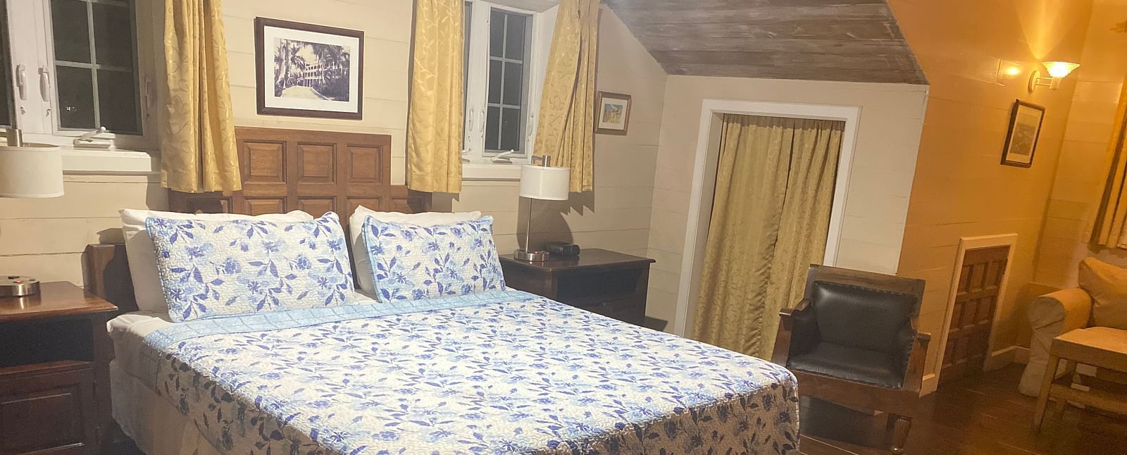 Bedroom with a bed, wooden floor, wooden furnishings, and beige walls | A Stone's Throw Away