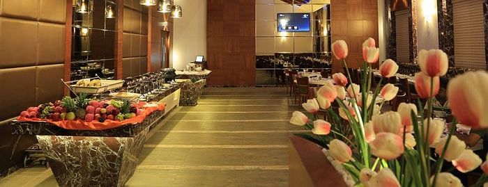 A beautifully decorated buffet counter with fresh flowers, soft lighting, and a luxurious dining ambience. - Dhanalakshmi Srinivasan Hotels, Perambalur