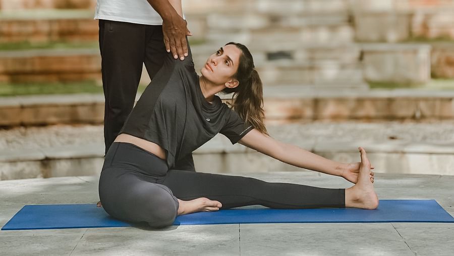 People doing yoga poses outdoors, stone steps, trees in background - Shreyas Retreat