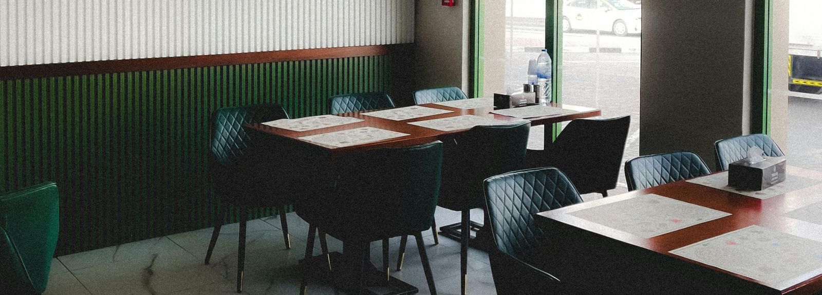 A small cafe interior with arched windows, simple tables, and chairs.