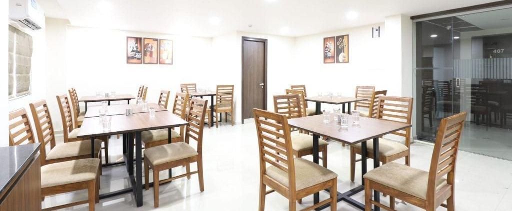 The interiors of Aranaya Restaurant at Pravasa Stay, Ahmedabad (Alba Premier), featuring well-arranged dining tables.