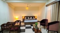 Executive Room at Pride Resort Rudraprayag featuring a double bed with lamps on both sides and sitting space in front of it 