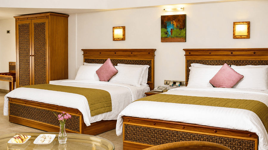 Golf Vista Cottage room with twin beds, wooden furnishings, and warm ambient lighting at Chariot Beach Resorts, offering a relaxing stay