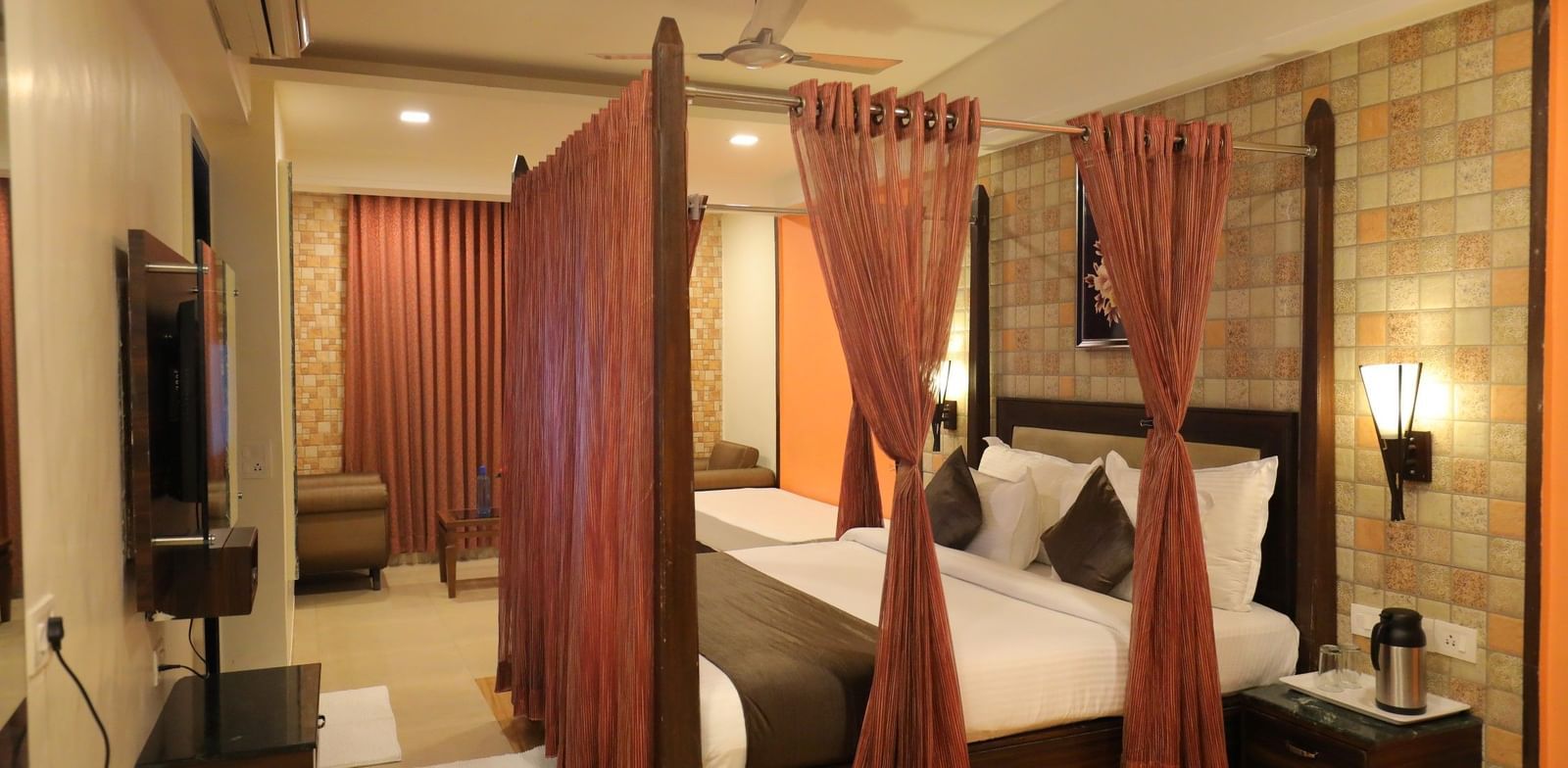 A wide view of a Krushnai Resort bedroom with a four-poster bed, dark wood furniture, and warm lighting.