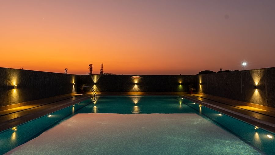 Overview of the swimming pool with the lights on and the evening sky after the sunset - Hotel Pai Vista, Mysore