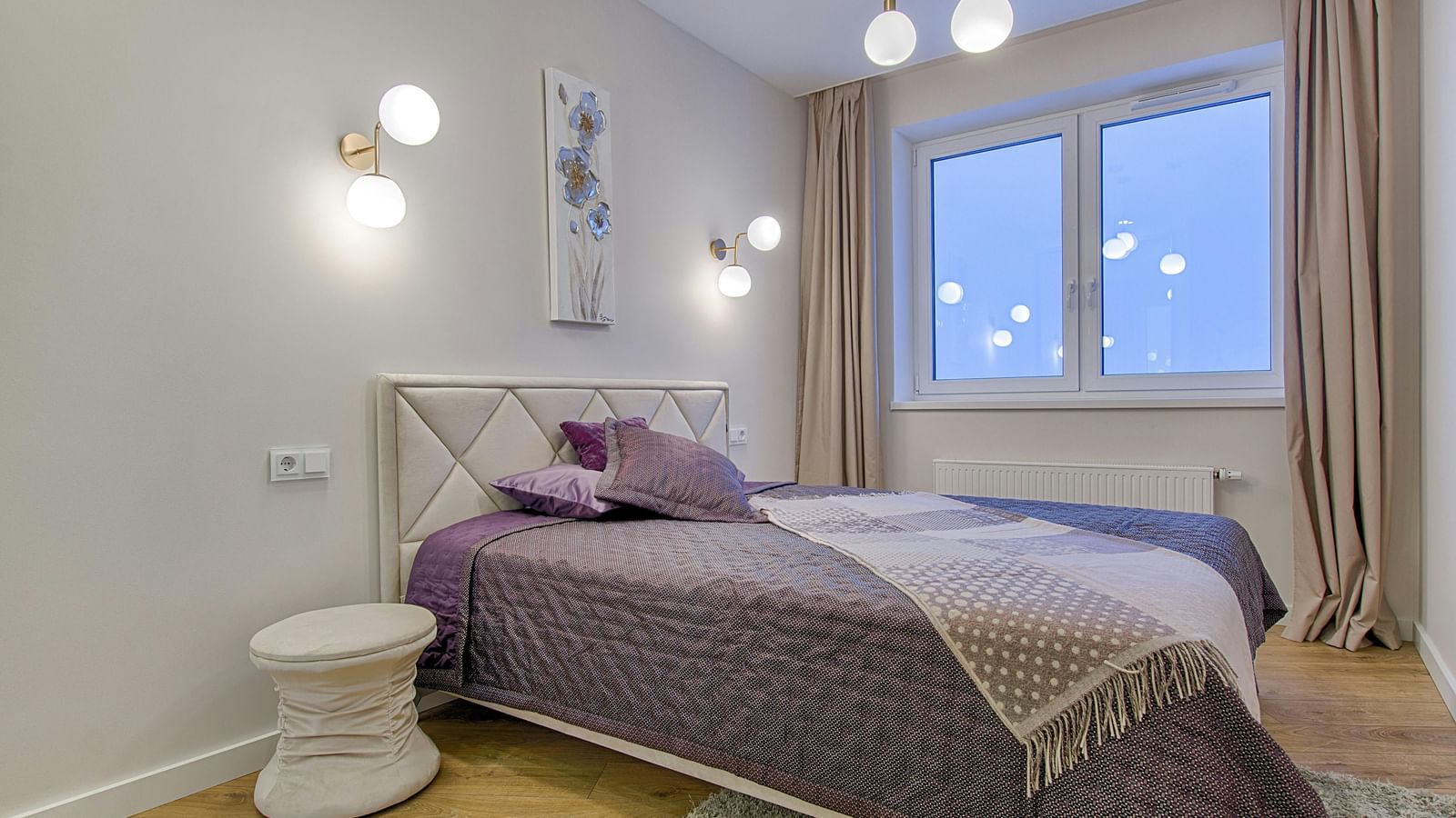 A modern bedroom with a double bed, light walls, and minimalist furniture.