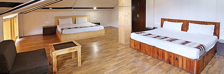 A room at DLS Hotel Devlok, Manali with a sloping roof line alongside a sofa chair and a coffee table