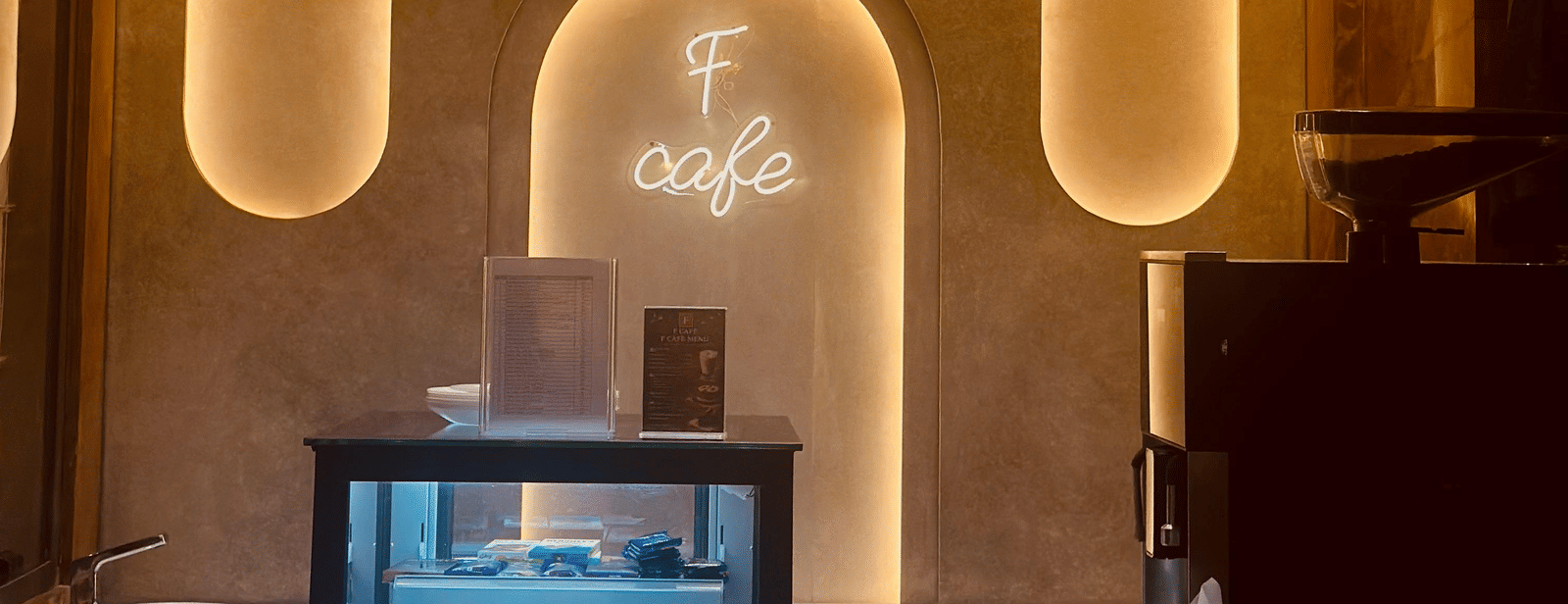 Front view of the F Cafe featuring a mini fridge with transparent door at F Hotels, Bengaluru.
