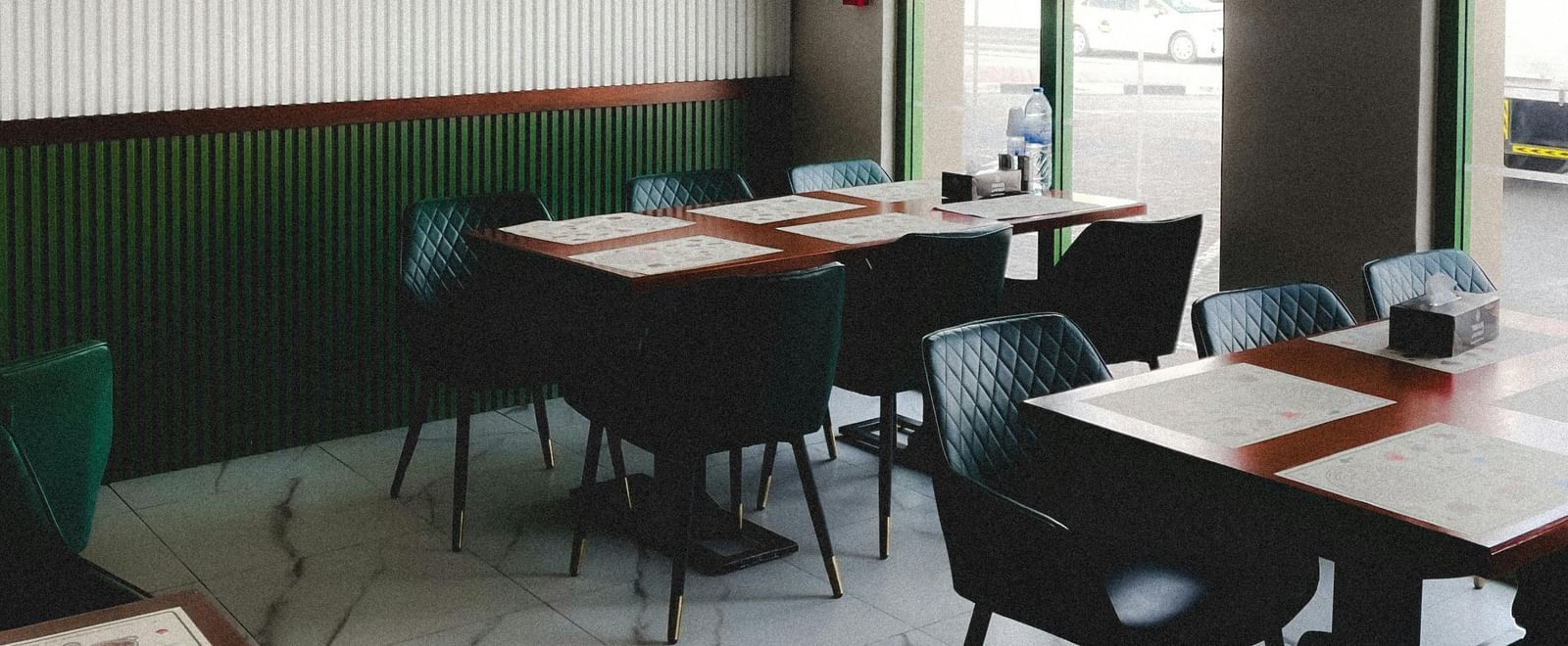 A small cafe interior with arched windows, simple tables, and chairs.