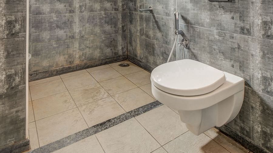 A spacious washroom at Harigovinda's JNStay, featuring a western toilet and a shower area