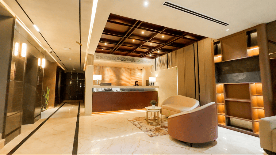 Full view of the lobby area at F Hotels, Bengaluru, with a person standing behind the reception desk.