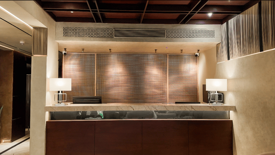 A beautiful reception desk with 2 brightly lit lamps on the corners at the lobby of F Hotels, Bengaluru.