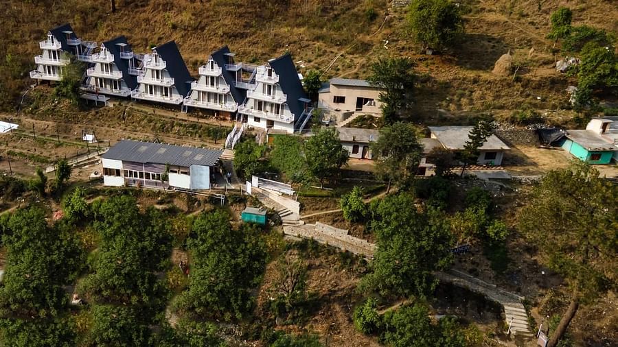 An overhead view of a group of modern, terraced buildings nestled on a sloping green hillside.