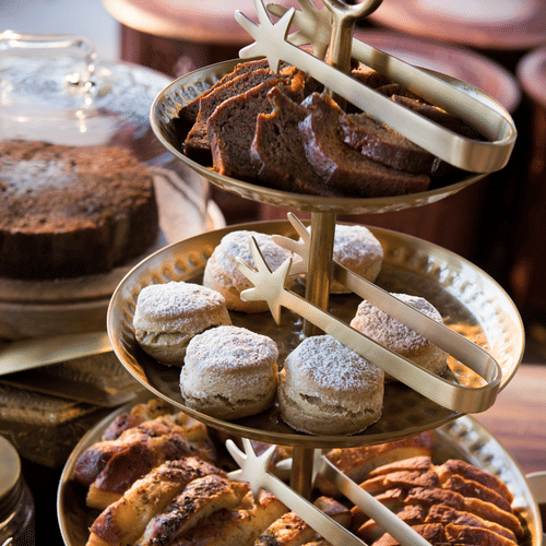 Three tiered tray containing cakes and serving tongs