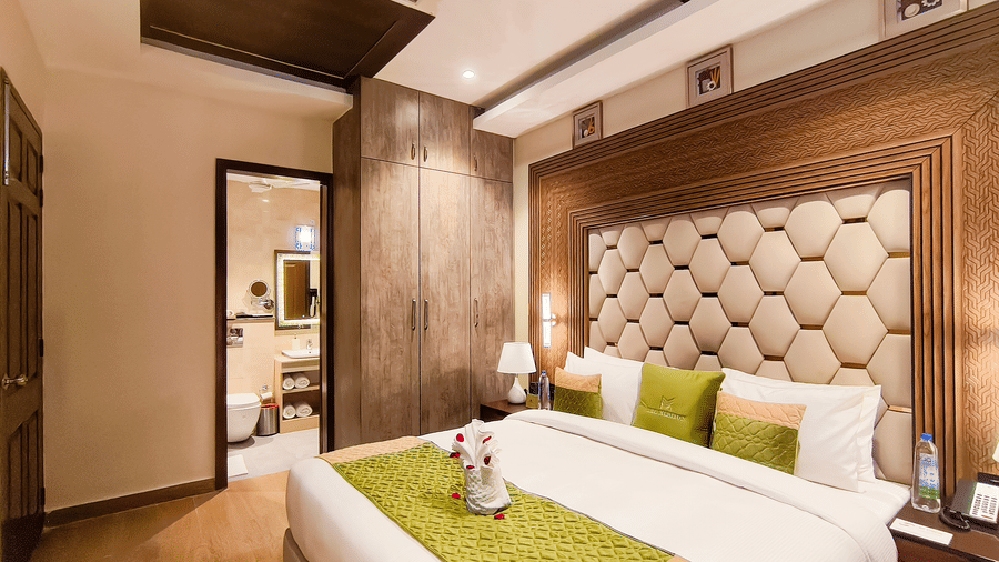 A spacious Junior Suite at The Meriton featuring elegant interiors with a king size bed and an attached bathroom.