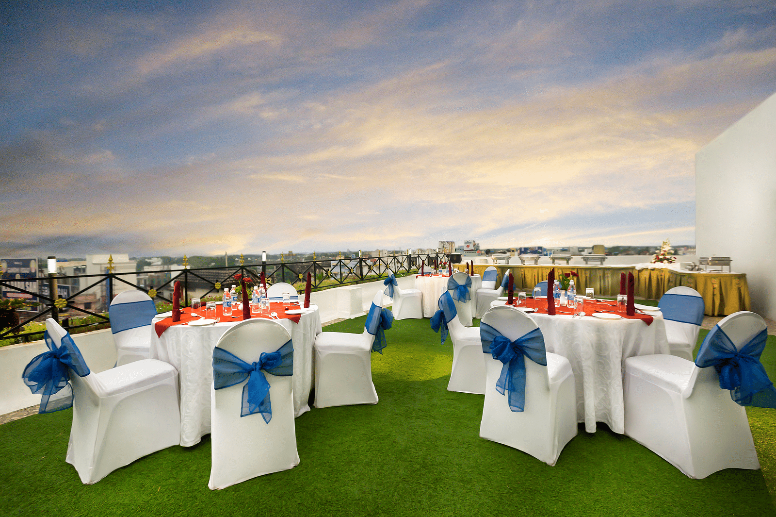 A banquet hall with white chairs laced with blue ribbons pointing towards the stage at Regency Kanchipuram by GRT Hotels.