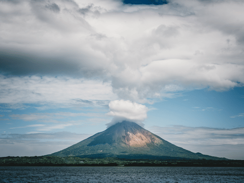 A volcano errupting from a mountain under a hazy sky
