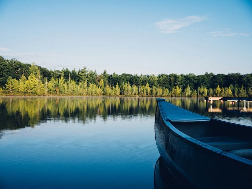 a view of a lake with trees in the background and a boat on the side