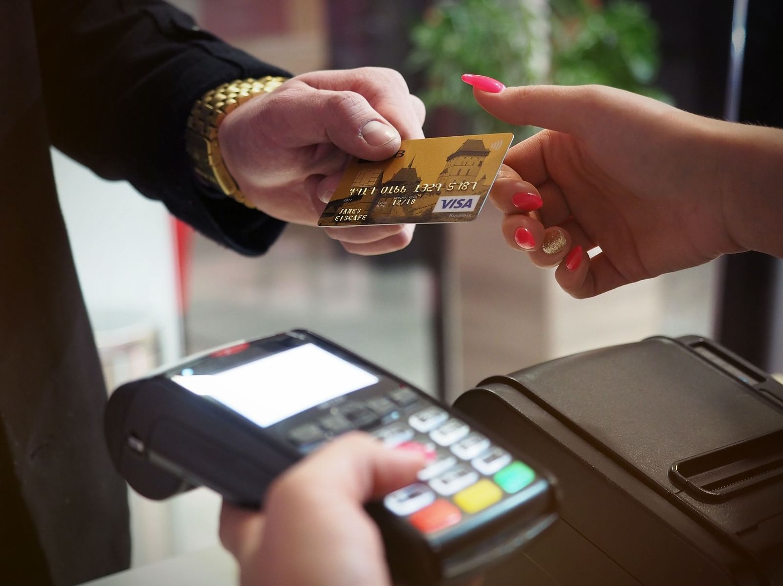 A person accepting a card with her right hand while holding a billing machine in the left