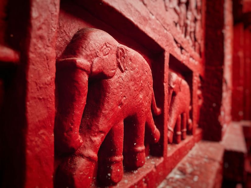 Close-up of red stone elephant carvings on an ancient temple wall.