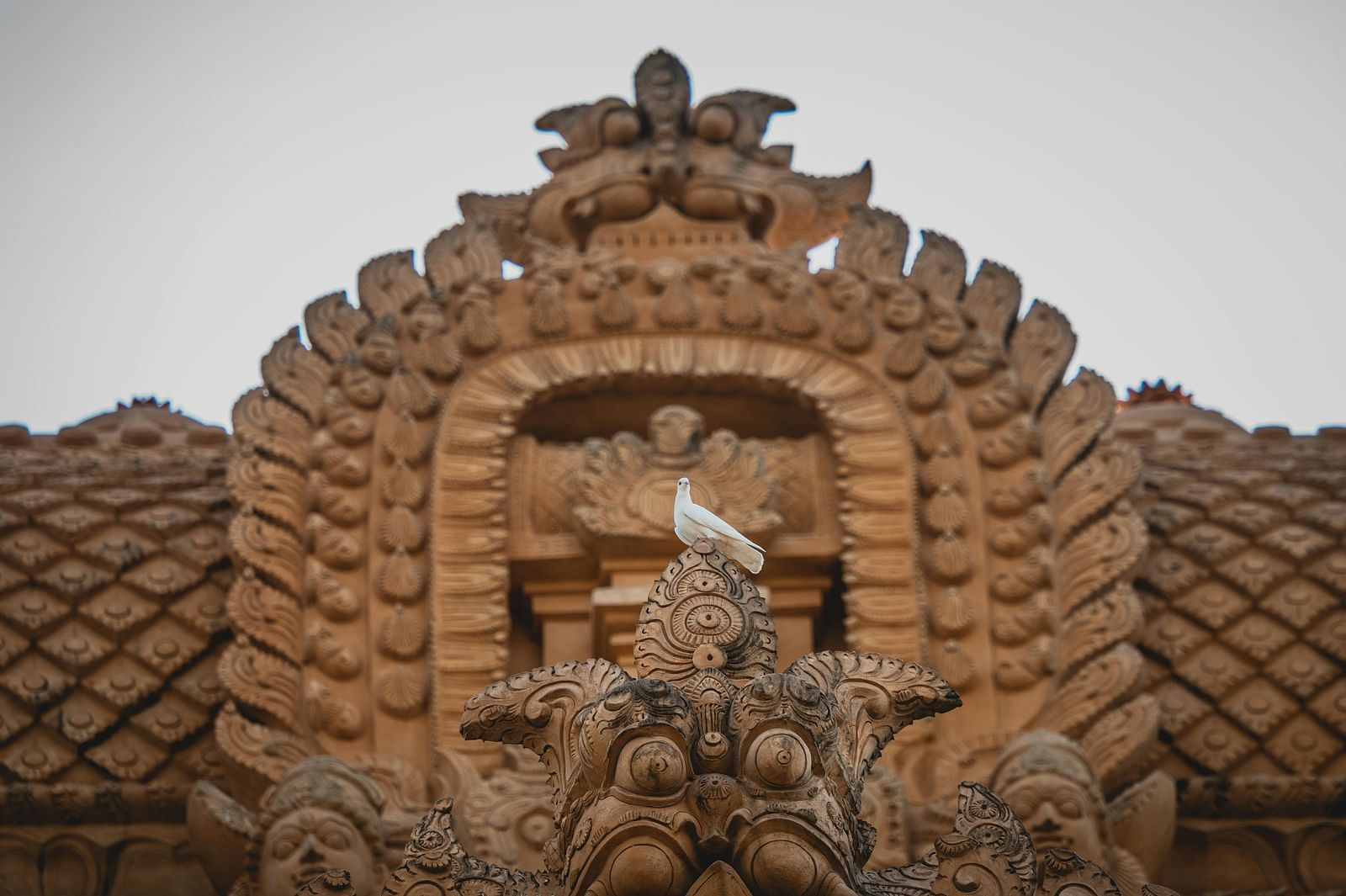 A white pigeon on a sculpture in front of a temple.