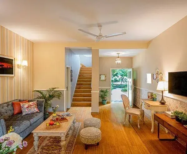 Spacious living room with warm lighting, modern decor, a staircase, and large glass doors opening to a garden at Karma Chalets.