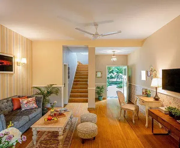 Spacious living room with warm lighting, modern decor, a staircase, and large glass doors opening to a garden at Karma Chalets.