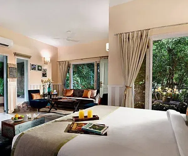 Cozy hotel room with twin beds, a seating area, and large windows letting in natural light and garden views at Karma Chalets.