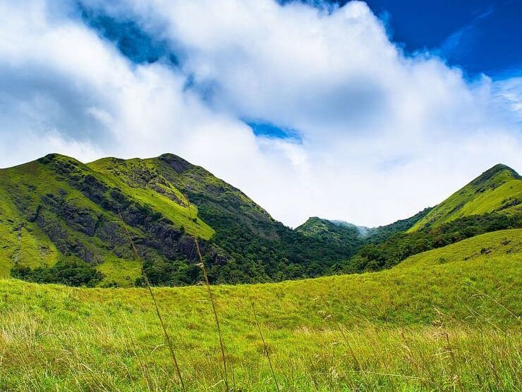 Expansive green hills with a bright sky and scattered clouds.