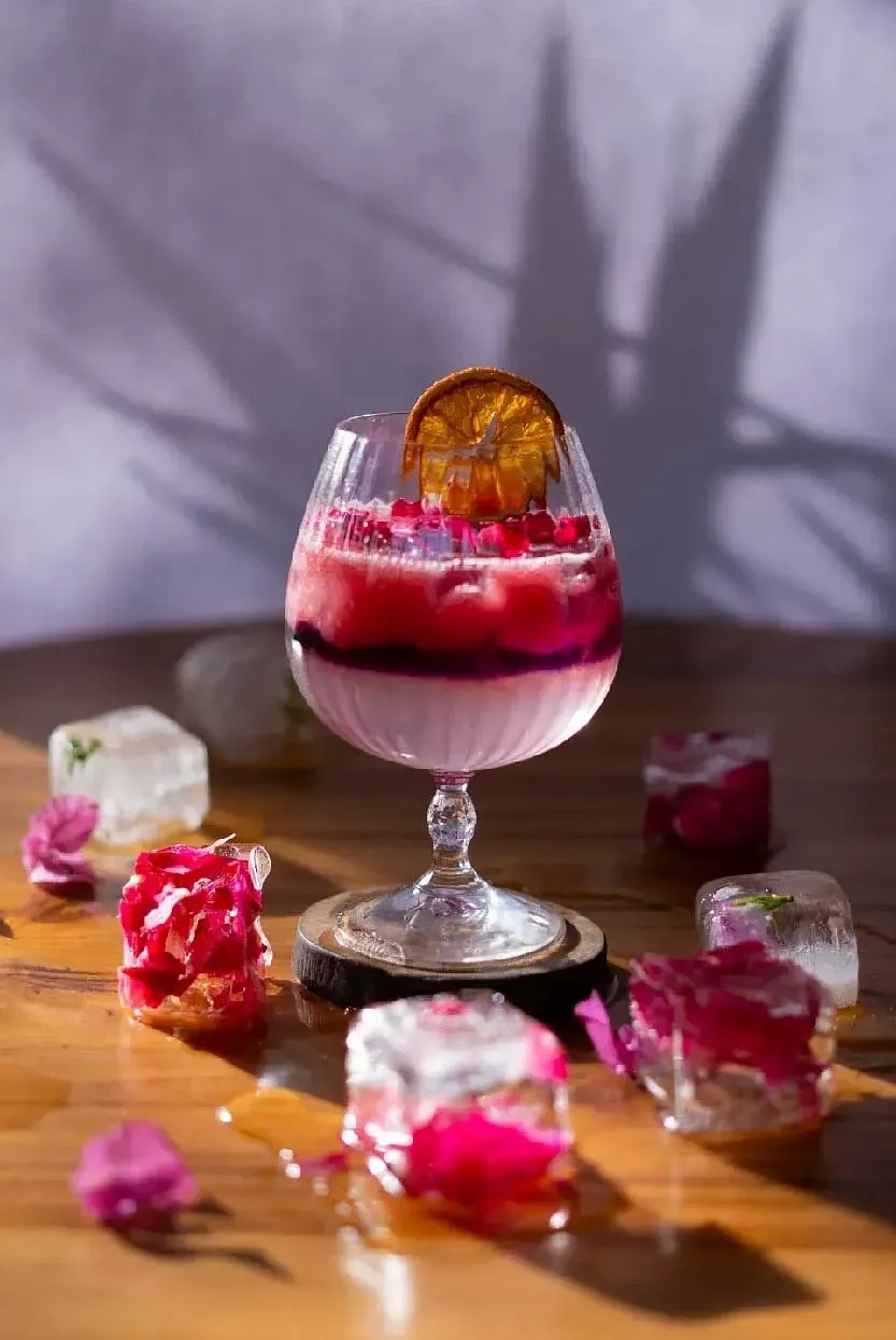 Purple dessert served in a glass with edible flowers and a dried orange slice at Karma Chalets
