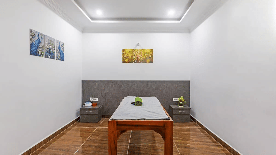 Minimalist spa room with a wooden table and decorative wall art at Siri Ambari Resorts and Spa.